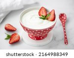 fresh homemade greek yogurt with fresh strawberries in a red bowl, close-up