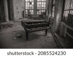 An old abandoned grand piano in an old abandoned building. An ancient musical instrument. The interiors of an abandoned Soviet building. Shabby walls.