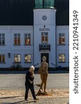 Small photo of Maribo, Denmark Oct 4, 2022 A woman walks by a statue on the main square.and the City Hall.