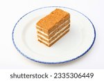 A piece of delicious layered honey cake, highlighted on a white background. A piece of honey cake on a white plate. Isolated object.