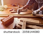 Small photo of Female craftsmen use tape measure to assemble wooden pieces. Professional carpenter at work measuring wooden planks.