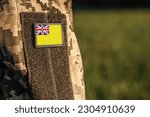 Small photo of Close up millitary woman or man shoulder arm sleeve with Niue flag patch. Troops army, soldier camouflage uniform. Armed Forces, empty copy space for text
