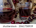 Small photo of Cherry and cherry juice or wine on a wooden table, a decanter and a glass with juice, a basket with cherries