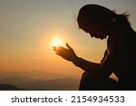 Silhouette woman on sunset background. Woman raising his hands in worship. Christian Religion concept background.