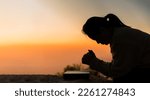Small photo of Silhouette of woman kneeling down praying for worship God at sky background. Christians pray to jesus christ for calmness. In morning people got to a quiet place and prayed. Banner with copy space.