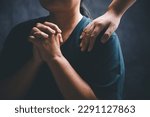 Small photo of Woman laying hands on a young female christian shoulder to empower and bless him while he feels discouraged in a home office, Christian faith, and christians praying laying on hands concept.
