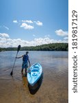 Small photo of Windigo village, Canada - july 2020 : Young man with a life jacket standing next to a kayak