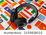 Small photo of Learning foreign languages online. Headphones and countries flags on the background.