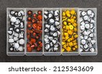 Small photo of Plastic multi-colored clips for a car in a container box on a gray background. Car clips, plastic fasteners, colorful plastic clips close-up in a box. Car clips and fasteners close-up.