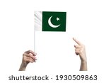 A beautiful female hand holds a Pakistan flag to which she shows the finger of her other hand, isolated on white background.