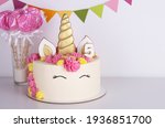 white delicate unicorn cake with pink lollipops on a white background. birthday cake