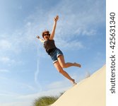 Woman Jumping Off A Sand Dune...