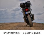 Enduro motorcycle traveler alone under a blue sky with white clouds.
