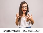 Annoyed angry young woman mad about spam message stuck phone looking at smartphone isolated against grey background, furious teen girl having problem with cellphone irritated by broken mobile