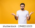 Young caucasian mistaken confused bearded man spreading hands oops gesture isolated on yellow background studio portrait People lifestyle concept