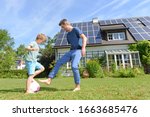 Father and son playing football in garden of solar paneled house