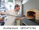 Chef Placing The Pizza In The...