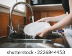 Woman washing dishes in kitchen ...