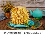 Lithuanian sakotis cake with teapot and flowers on wooden table.