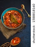Small photo of Pomodoro, Arabiatta or Marinara Sauce in a blue bowl, with a wooden spoon and chili flakes, presented in a rustic style.