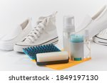 Small photo of Leather loafers, canvas sneakers and cleaning kit on white background. Brush off the dirt, wash and shine them up with a sponge.