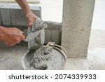 bricklayer scooping mixed mortar on brick to install bricks block on construction site, selective focus           