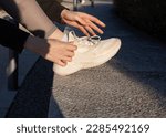 a woman ties her shoelaces on sneakers while jogging in the park