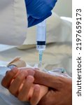 Small photo of Close-up of Dad holding his sick child's hand during a medical procedure wherein medication is infused directly into the patient's vein.