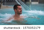 Small photo of Portrait of an young man is enjoying and having relax in a whirlpool bath tube in a luxury wellness center.