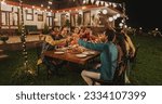Small photo of Big Indian Family Celebrating Diwali: Family Gathered Together on a Dinner Table in a Backyard Garden Full of Lights. Group of Adults Having a Toast and Raising Glasses on a Hindu Holiday