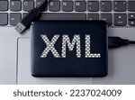 Small photo of XML (Extensible markup language) - acronym on an external drive in gray letters on the background of a laptop. Internet concept