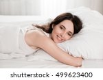 Young girl in the morning,lying in bed sleeping after hard work day tired.Nude makeup. Warm toning image.Fresh bedclothes,furnishing shop,new day, weekend,washing or laundry concept.