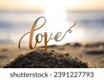 Small photo of Black outlines of word Love at dawn and sunset on the background of sea waves on seashore. Stick contours in shape word Love in sand of setting and rising sun. Concept Love infatuation Valentine's Day