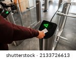Close up of unrecognizable swiping card passing turnstile to enter building. The hand holds the card. Access is allowed.