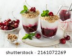 Small photo of delicious cherry cream trifle dessert in glass, white background
