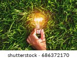hand hold light bulb on grass  with sunset power energy concept nature