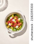 Small photo of Tuna tartar in ceramic bowl on white table in sunny day. Tuna and avocado tartar with cream cheese in restaurant menu. Appetizer from tuna and avocado with shadow from wine glass