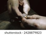 Small photo of hand of a goldsmith punches a hallmark into a golden ring on an anvil, close up with copy space, focus, narrow depth of field