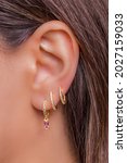 Small photo of Woman ear with mulriple piercings wearing beautiful earrings with zirconia- details capture