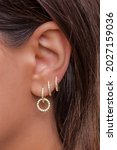 Small photo of Woman ear with mulriple piercings wearing beautiful earrings with zirconia- details capture