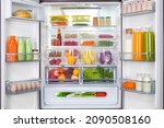 Small photo of plastic containers with different fruits and vegetables in a open fridge. frozen food storage.