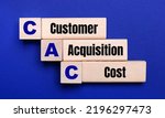 Small photo of On a bright blue background, light wooden blocks and cubes with the text CAC Customer Acquisition Cost