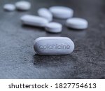 Small photo of Colchicine tablet close up of medication used to treat gout and Behcet disease, pericarditis, familial mediterranean fever