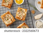 Mini tarts with puff pastry, pieces of pear, blue cheese, walnuts and honey on a concrete background. Top view
