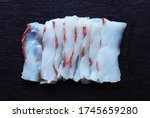 Small photo of Photography of a filet of meagre cut like sashimi on slate background for food illustrations