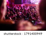 Defocused spectators sit in the hall and watch a concert. People in the auditorium watching the performance. Theater audience. Out of focus