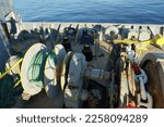 Small photo of Forward port side mooring winch and anchor windlass with chain and heaved up green manila rope on working drum of cargo container vessel during passing Mediterranean Sea during sunny weather.