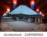 Small photo of Jung-gu, Seoul, South Korea - May 10, 2022: Low angle and night view of Cheongsachorong(traditional Korean lantern) on the eaves of tile house against N Seoul Tower at Namsangol Hanok Village