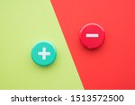 Flat lay of green plus and red minus symbol plastic botton on green and red background with copy space. Concept of difference, opposites plus vs minus or pros vs cons.