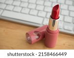 Small photo of Red lipstick with keyboard computer background on wooden table. Online internet romance scam or swindler in website application dating concept. Love is bait or victim.
